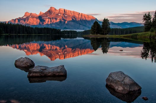 Stunning view of a mountain reflecting in a calm lake during sunset in Banff National Park.