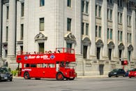Red double-decker tour bus on city street in Montreal, Canada with historic architecture.