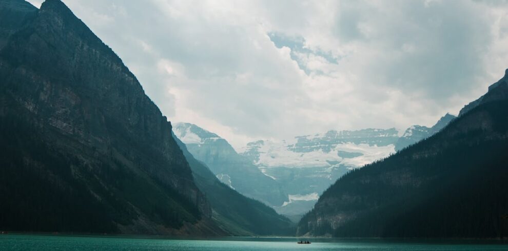 Serene view of Lake Louise and surrounding mountains under cloudy skies.