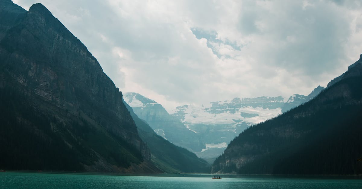 Serene view of Lake Louise and surrounding mountains under cloudy skies.